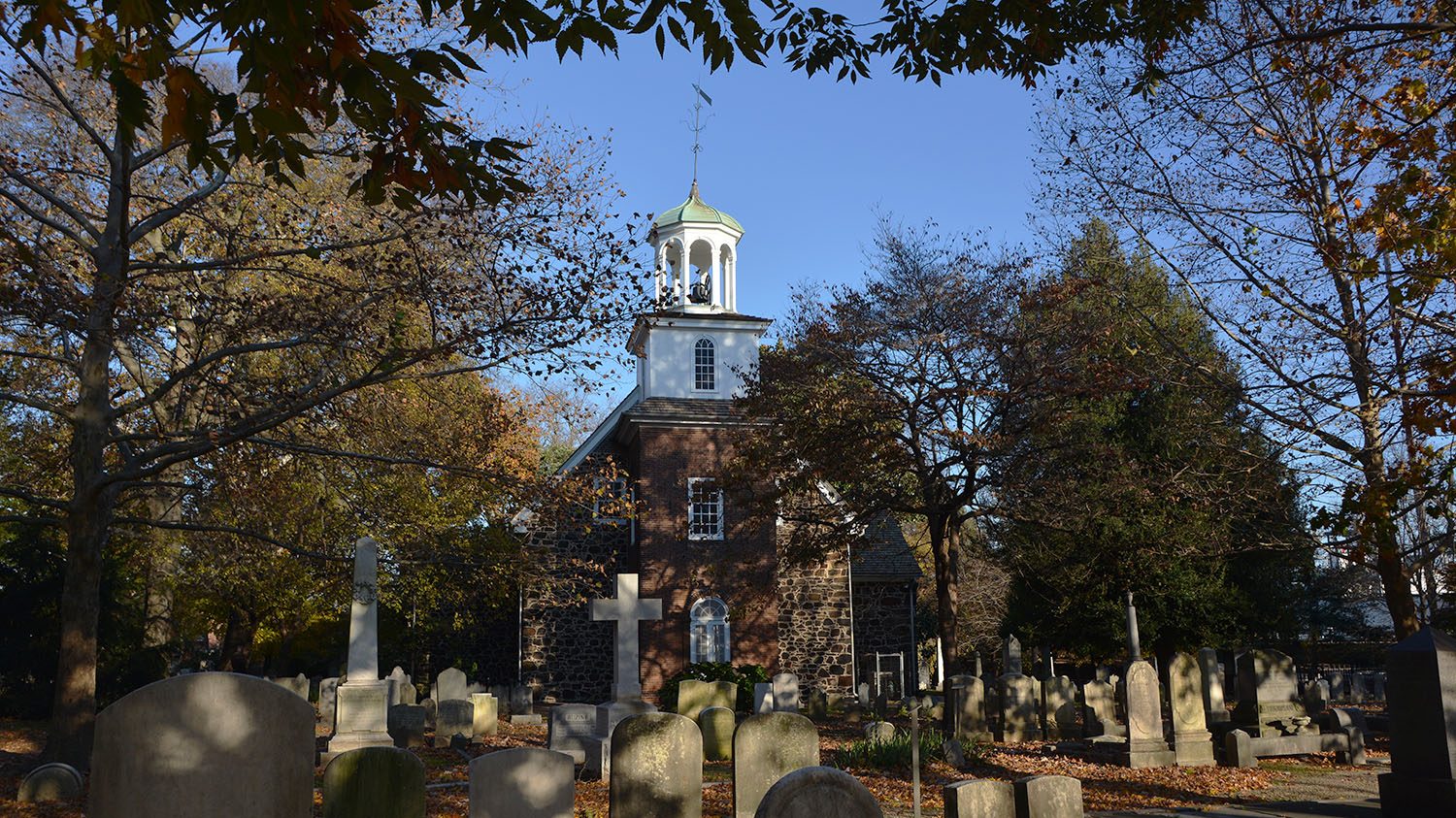 A photo of Old Swedes Church and graveyard in the fall.